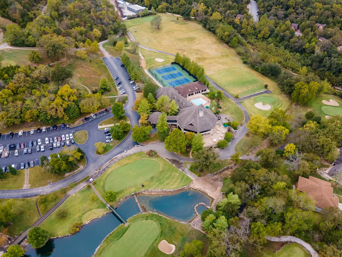 A wide-angle exterior shot featuring the resort’s amenities: a golf course, tennis courts, swimming pool, and clubhouse. The vibrant greenery and open space highlight the abundance of leisure activities available to guests.