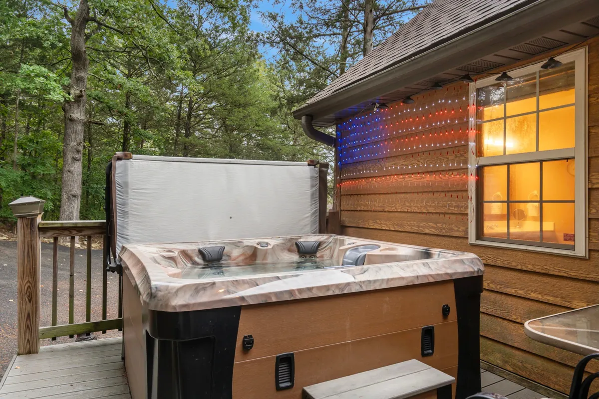 This image displays a private hot tub nestled on a wooden deck, surrounded by trees. The tranquil setting highlights the connection to nature, with soft lighting suggesting a relaxing atmosphere for both day and evening use.