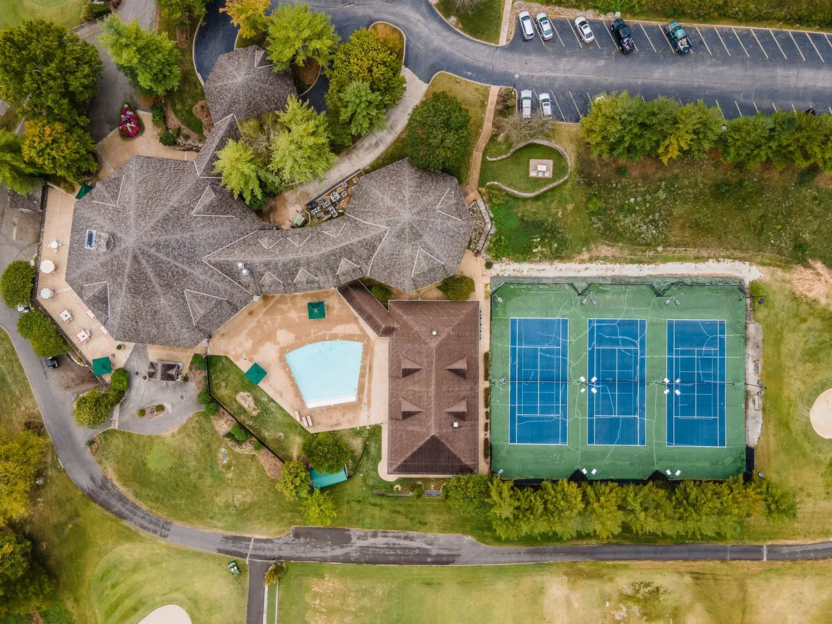 The resort’s pool and tennis courts, surrounded by greenery and the main building. Guests are seen lounging and enjoying active recreation, highlighting the breadth of amenities available at StoneBridge Resort.