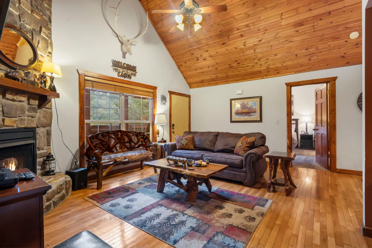 This image features a cozy living room with a glowing propane fireplace, a comfortable sofa, a wooden ceiling, a coffee table, and tasteful artwork. The setting exudes warmth and a sense of togetherness, inviting guests to relax, socialize, or gather for family activities.