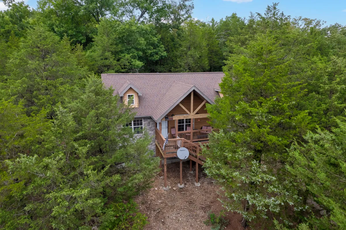 A peaceful wooden deck at the front entrance of the lodge, surrounded by mature trees, offering a tranquil spot for outdoor relaxation and a seamless connection to the natural environment.