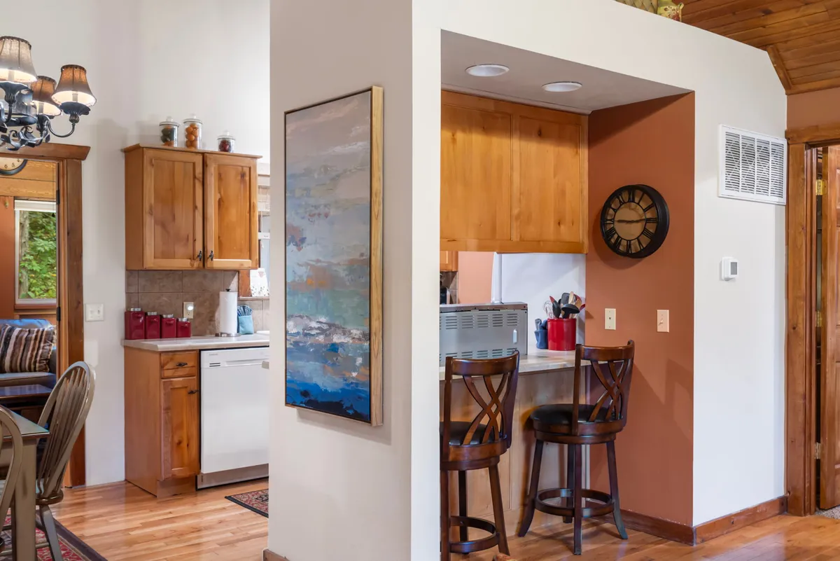 A wide view of a cozy kitchen and dining area featuring a spacious kitchen with counter seating, stylish wall art, and an adjacent dining area. Warm lighting and a thoughtful open layout invite both chefs and guests to mingle while meals are prepared.